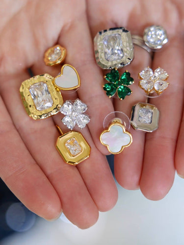 Collection of gold and diamond earrings held in a hand against a blurred background