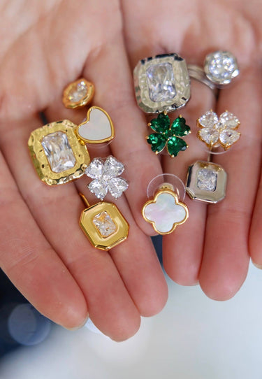 Collection of gold and diamond earrings held in a hand against a blurred background